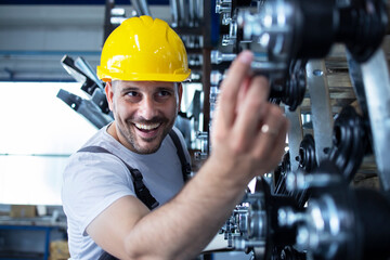 Shot of caucasian factory worker in yellow hardhat checking quality of products in industry.