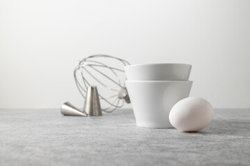 composition of ceramic bowls, bag attachments, kitchen machine whisk and white eggs