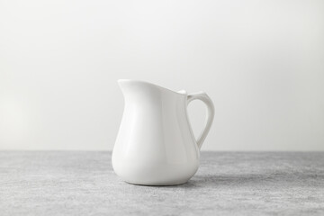 beautiful vintage milk jug of white color on a light concrete background
