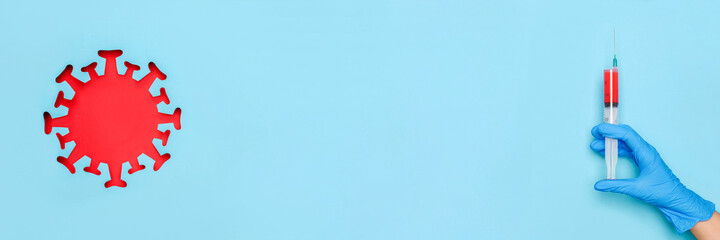 Hand in latex glove hold syringe with vaccine drug and abstract red coronavirus, virus, bacteria, microbe, blue background. Concept vaccination and infectious diseases, pandemic Covid -19 Banner