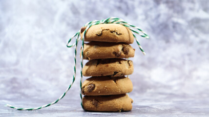 American chocolate chip cookies stacked on top of each other with green thread on a gray...