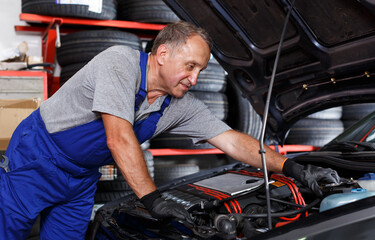 Fototapeta na wymiar Skilled mechanic technician working in the service station, repairing car