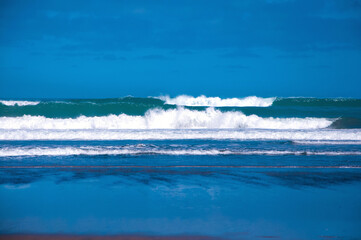 Big powerful ocean waves hitting sandy shore of Ninety Mile Beach, North Island, New Zealand