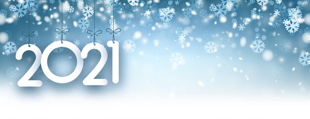 2021 paper sign hanging on ribbons on snowy background.