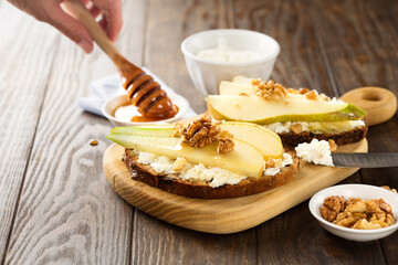 Appetizer bread bruschetta with pear, honey, hazelnuts and cottage cheese on old rustic wooden background
