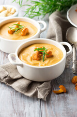 Mushroom cream soup with chanterelles and herbs on dark rustic wooden background.