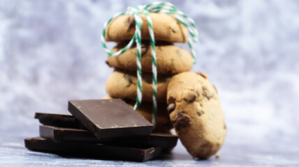 American chocolate chip cookies stacked on top of each other with green thread on a gray background. Traditional rounded crunchy dough with chocolate chips. Bakery. Delicious dessert, pastries.