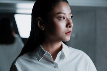 Asian woman in white shirt looking at the right hand side of the camera.