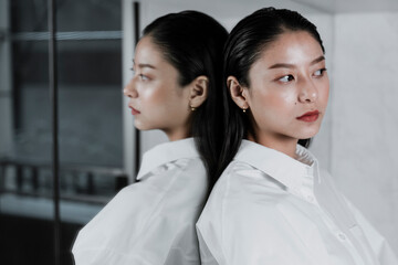 Obraz premium Asian woman leaning at the mirror.