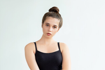 Home outfit. Casual look. Pretty young woman in black sleeveless top and bun hairstyle looking at camera isolated on neutral. Aesthetic cosmetology. Beauty treatment