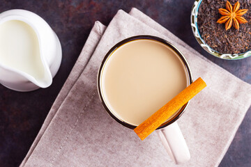 Masala chai tea. Traditional indian drink - masala tea with spices on dark background. Ceramic cup of spices tea and white milk jug