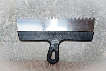 putty knife on gray grunge cement wall background. spatula for repair and construction. building...