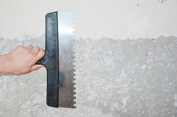 Damaged wall repair. hand hold putty knife on gray grunge cement wall background. spatula for...