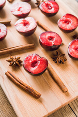 Sliced red plums with cinnamon sticks and anise stars on the wooden table. Selective focus. Shallow depth of field.