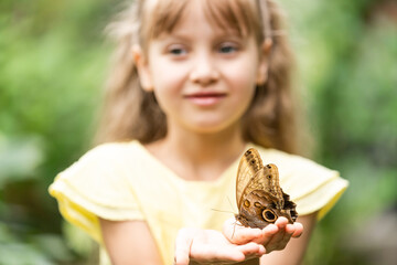 cute little girl holding living beautiful butterfly on her hand