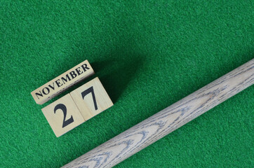 November 27, Number cube with a snooker stick on a green background, snooker table.