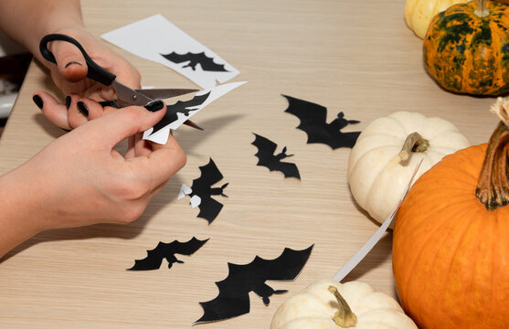 A man carves bats as decorations for a Halloween party.