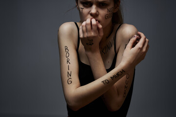 Emotional woman with inscriptions on her body gestures with hands lifestyle frustration stress gray background