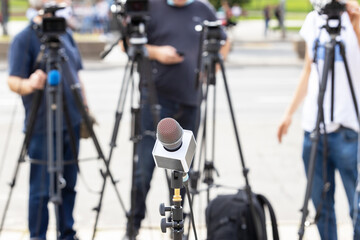 Microphone in focus at news conference, blurred camera operators in the background