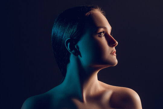 Neon Light Portrait. Female Beauty. Profile Silhouette Of Confident Woman With Bare Shoulders In Blue Glow Isolated On Dark Copy Space Background. Face Contouring. Skincare Wellness.