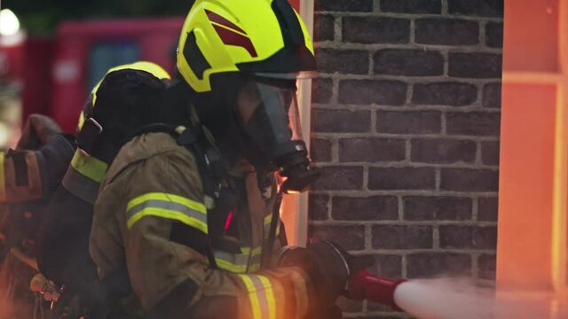 two firefighters extinguishing fire, burning house. High quality 4k footage