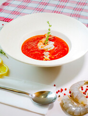 Delicious cold tomato soup or gazpacho with shrimps in a white plate on a white table. Decor. Top view. Selective focus. Super short focus