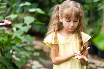 cute little girl holding living beautiful butterfly on her hand