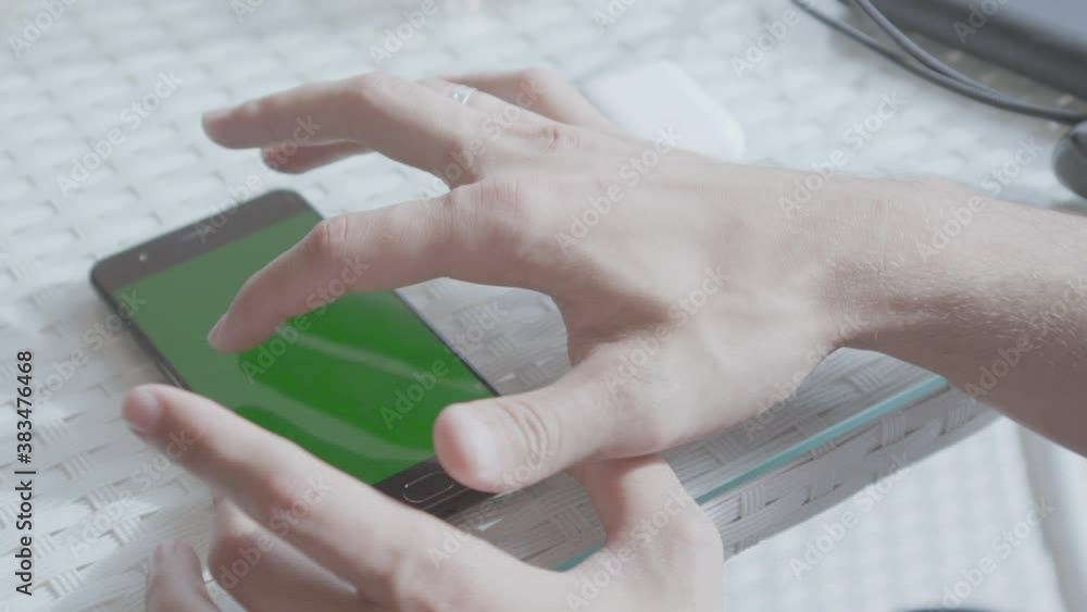 Poster close-up of man tapping on green phone screen. stock. man is holding phone with green screen on tabl