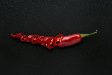 Isolated red hot chili pepper on black stone background, ideal ingredient for spicy and passionate...