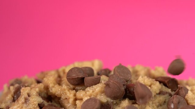 Chocolate chips falling on raw cookie dough in slow motion