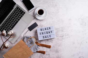 Black Friday Sale words on lightbox with cup of coffee, laptop and shopping bag top view flat lay on white background