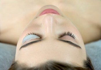 Close up of beauty model's face with perfect fresh skin and long eyelashes, lash lift laminate...