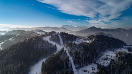 Fototapeta premium Aerial view of white winter in the mountains and ski resort. Sunny winter day in alpine mountains. Winter holidays in Austria, Switzerland, Italy, Poland.