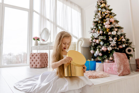 Cute little blonde girl opens a Christmas present. Happy Christmas baby.