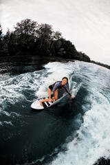 High angle view of a young smiling woman riding on surf board and look at camera