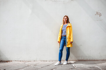 happy woman standing on the street in front of a wall
