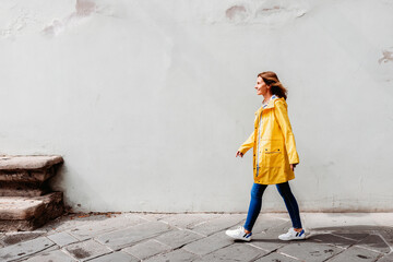 happy woman walking on the street in front of a wall