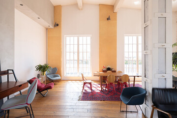 modern design of a huge white bright room with two red sofas and many large windows. full of sunshine. high ceiling and wooden parquet