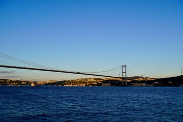 Fototapeta na wymiar Tourist boats sail under the bridge in Istanbul. Traveling on the Bosphorus. Panoramic view, View of the First Bosphorus Bridge sailling Bosporus.
