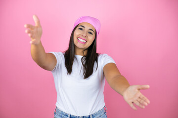 Young beautiful woman wearing pink headscarf over isolated pink background looking at the camera smiling with open arms for hug