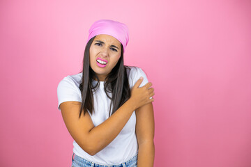 Young beautiful woman wearing pink headscarf over isolated pink background with pain on her shoulder and a painful expression