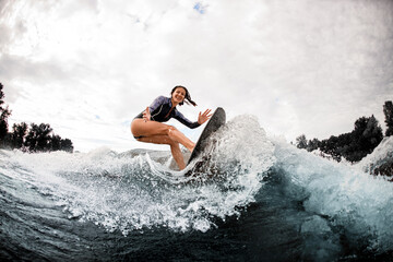 young cheerful woman is engaged in wake surfing - obrazy, fototapety, plakaty