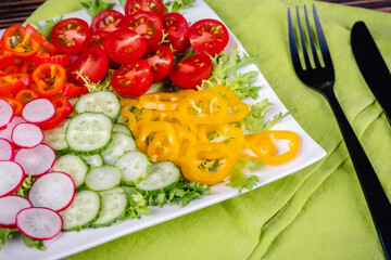 Fresh chopped vegetables on a plate on a wooden table.