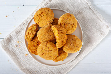 Homemade golden brown corn biscuits on a white plate and white wooden table, top view