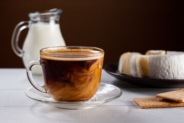 A cup of hot american black coffee with cream poured over. Tasty breackfast with creamy Camembert...
