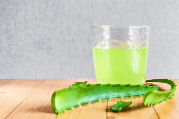 A glass of aloe juice. Aloe Vera leaves and juice on a wooden background