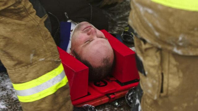 Firefghters lifting injured man. Rescue after car crash accident. High quality 4k footage