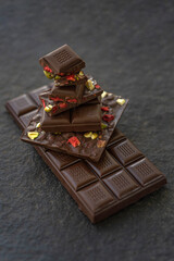 Chocolate bars handmade with strawberries and pistachios on a black background. Craft vegan chocolate