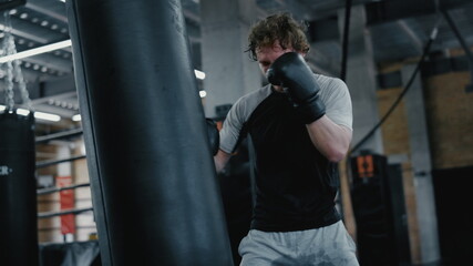 Fototapeta na wymiar Ambitious fighter training in fitness center. Kickboxer warming up at gym