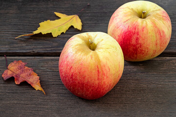 Apples with autumn leaves on wooden background